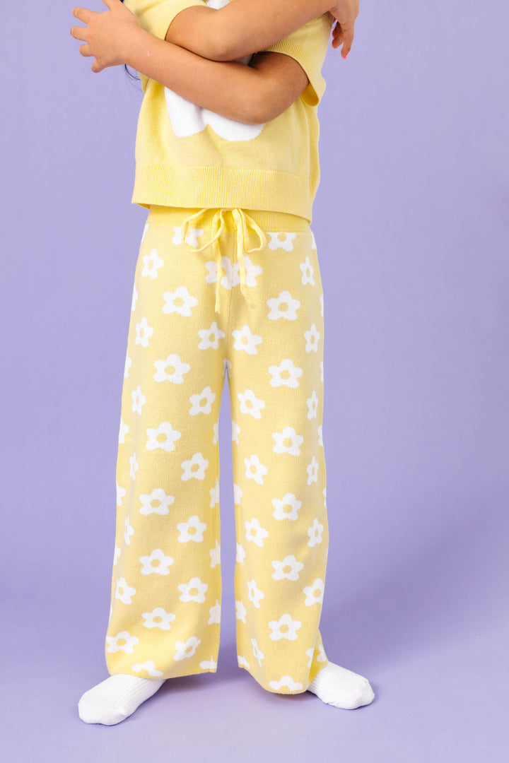 little girl wearing sunny yellow cotton knit sweater pants with drawstring waistband and all over white flower design for spring