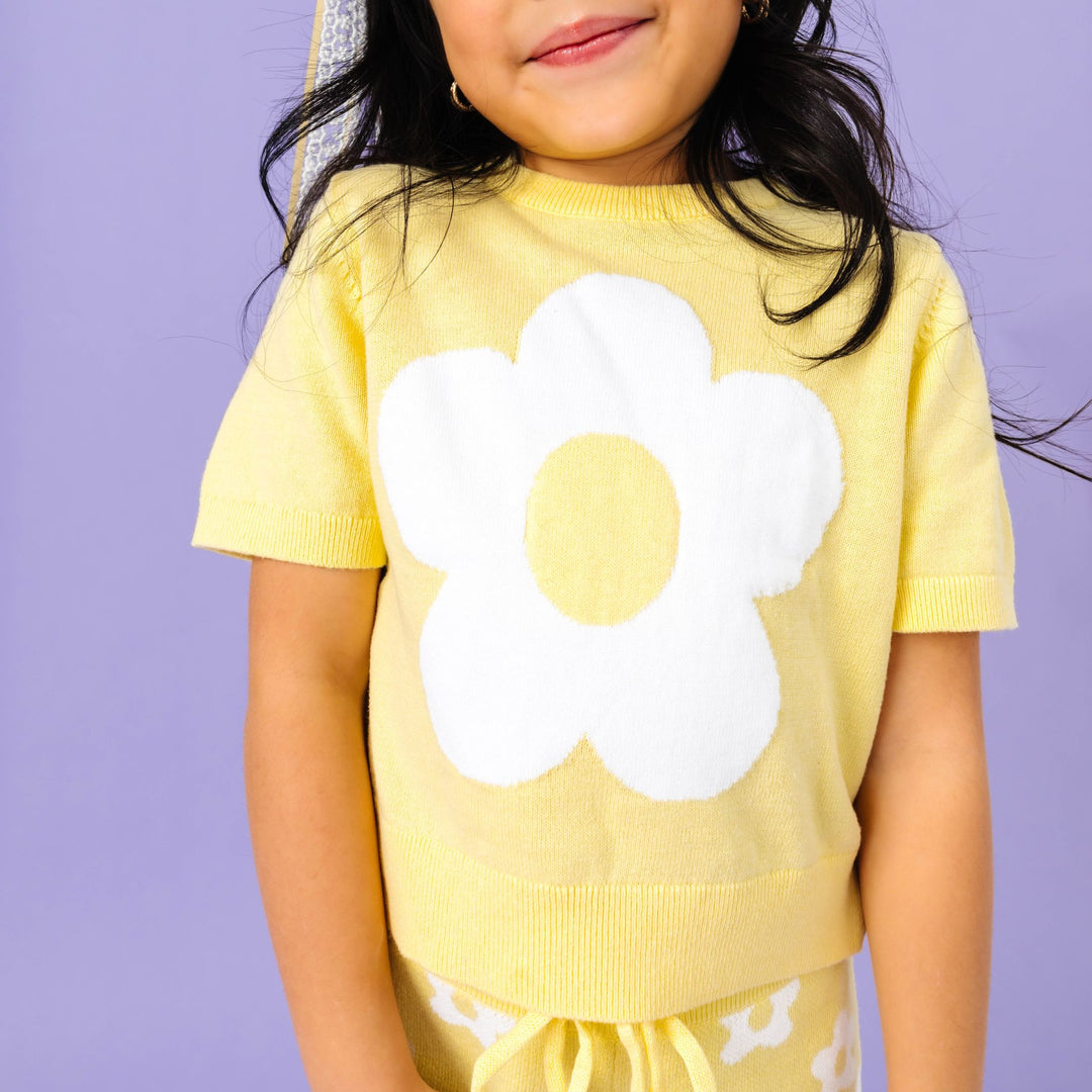 little girl in short sleeve cotton knit sweater with white flower design paired with matching floral pants