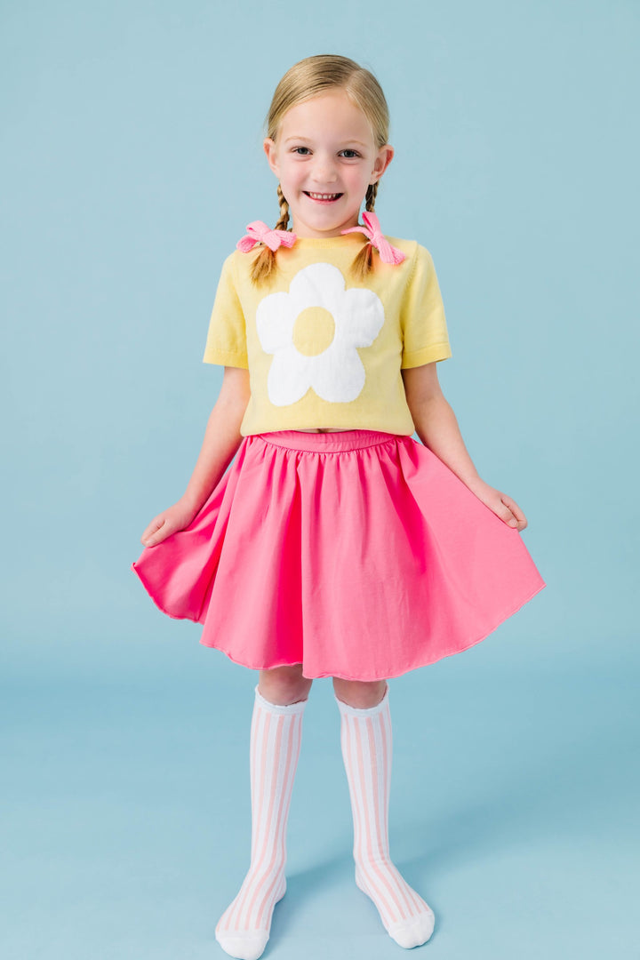 little girl with yellow short sleeve knit flower sweater paired with taffy pink cotton blend skort, pink and white striped knee socks and pink knit pigtail bows for spring