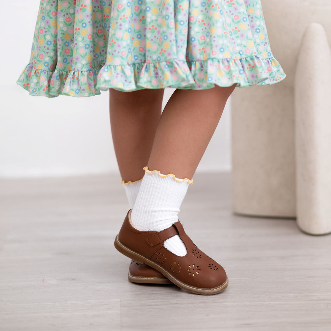 little girl in white ribbed midi socks with yellow lettuce trim and brown mary janes paired with mint floral spring twirl dress