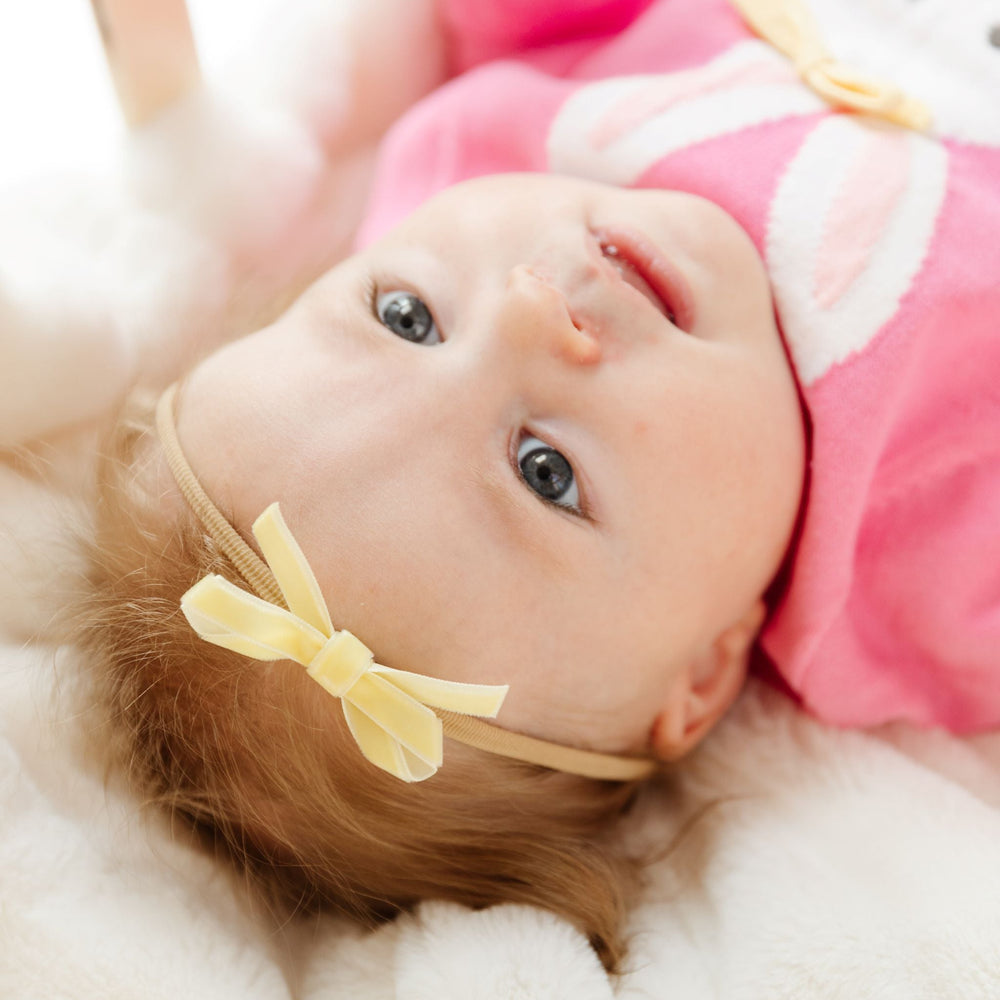 baby girl in pastel yellow velvet ribbon baby bow on stretchy nylon headband to match easter bunny sweater