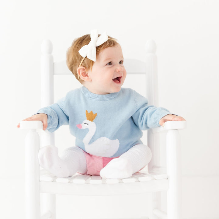 baby girl in swan princess knit pullover set with white velvet bow and cable knit tights