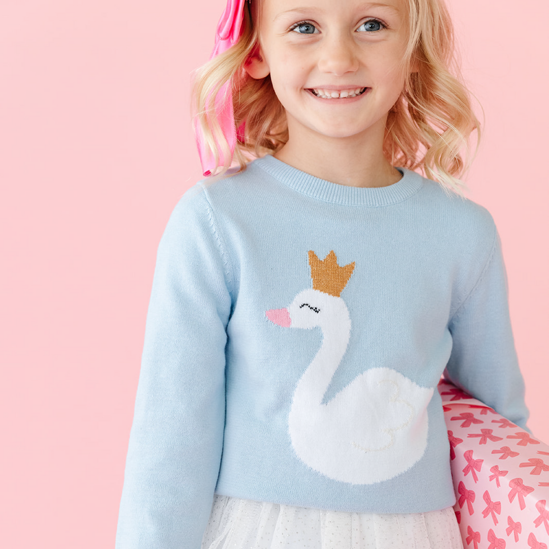 Little girl in light blue knit pullover with swan in a gold sparkly crown