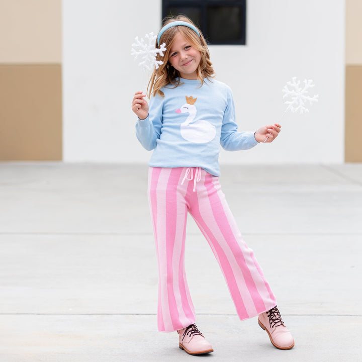 girl in light blue pullover sweater with swan princess design, blue sparkle headband and matching two tone pink sweater pants for Christmas