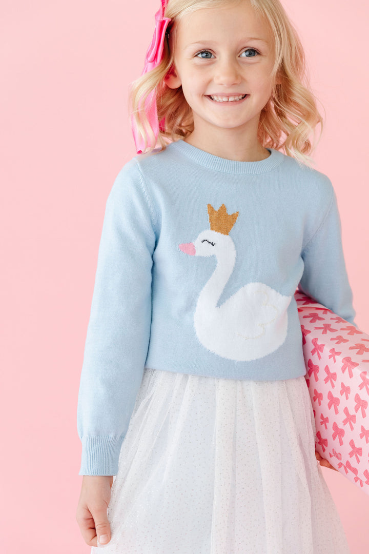 little girl in light blue knit sweater with sparkly swan princess detail layered over winter white tulle and velvet dress