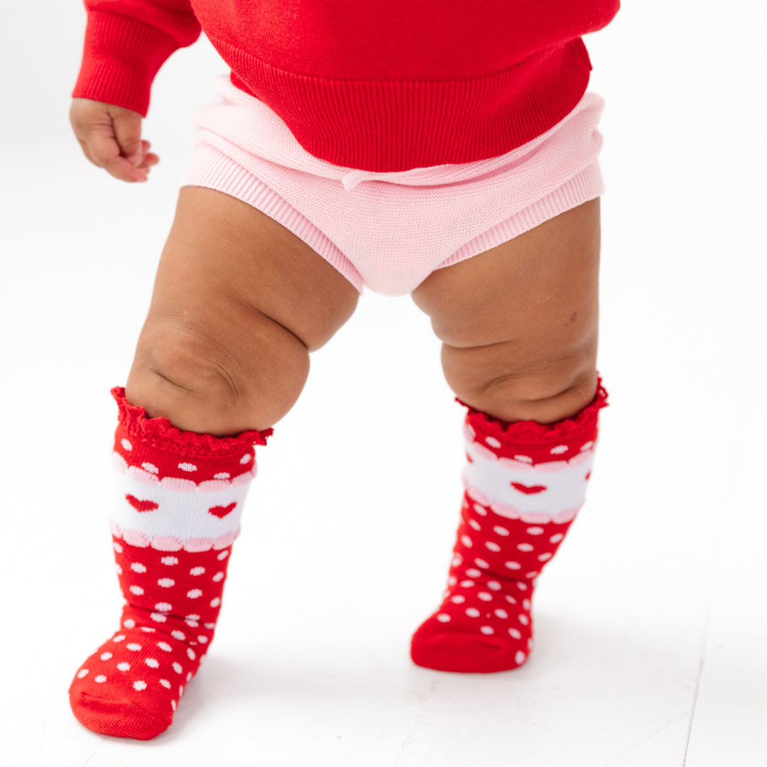 baby girl in pink cotton knit sweater bloomers with coordinating red dot valentines themed knee highs and red sweater