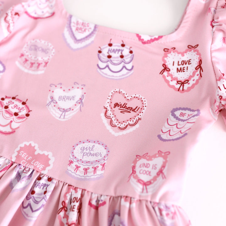 print closeup for pink Valentine's cake print dress with words of affirmation for girlhood