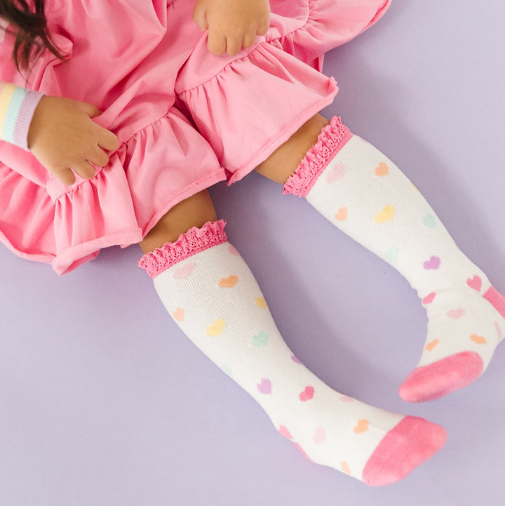 little girl wearing taffy pink ruffle skirt twirl dress and rainbow heart valentines day socks