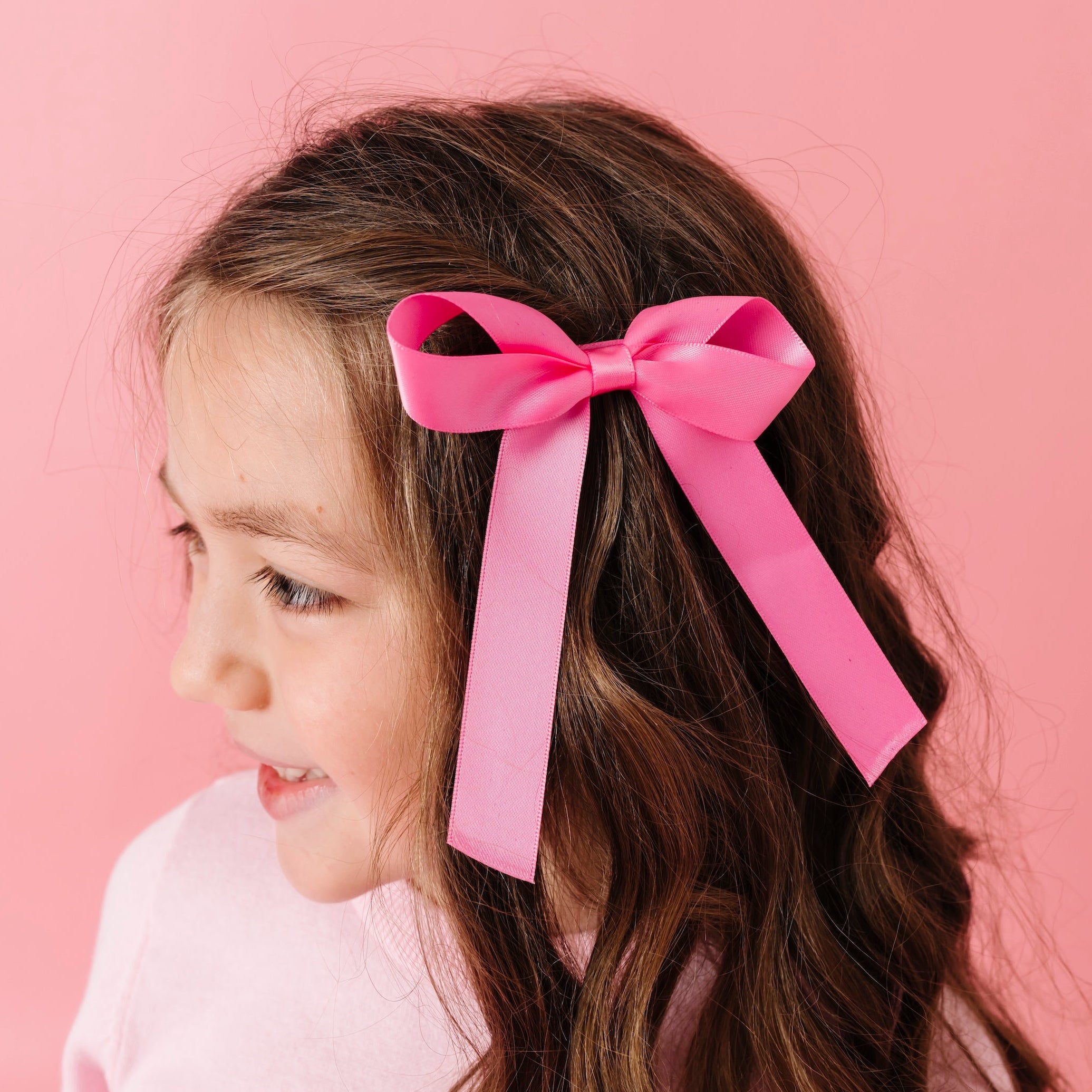 girl wearing girls taffy pink satin hair bow on alligator clip covered in matching satin with matching pink sweater for valentine's day