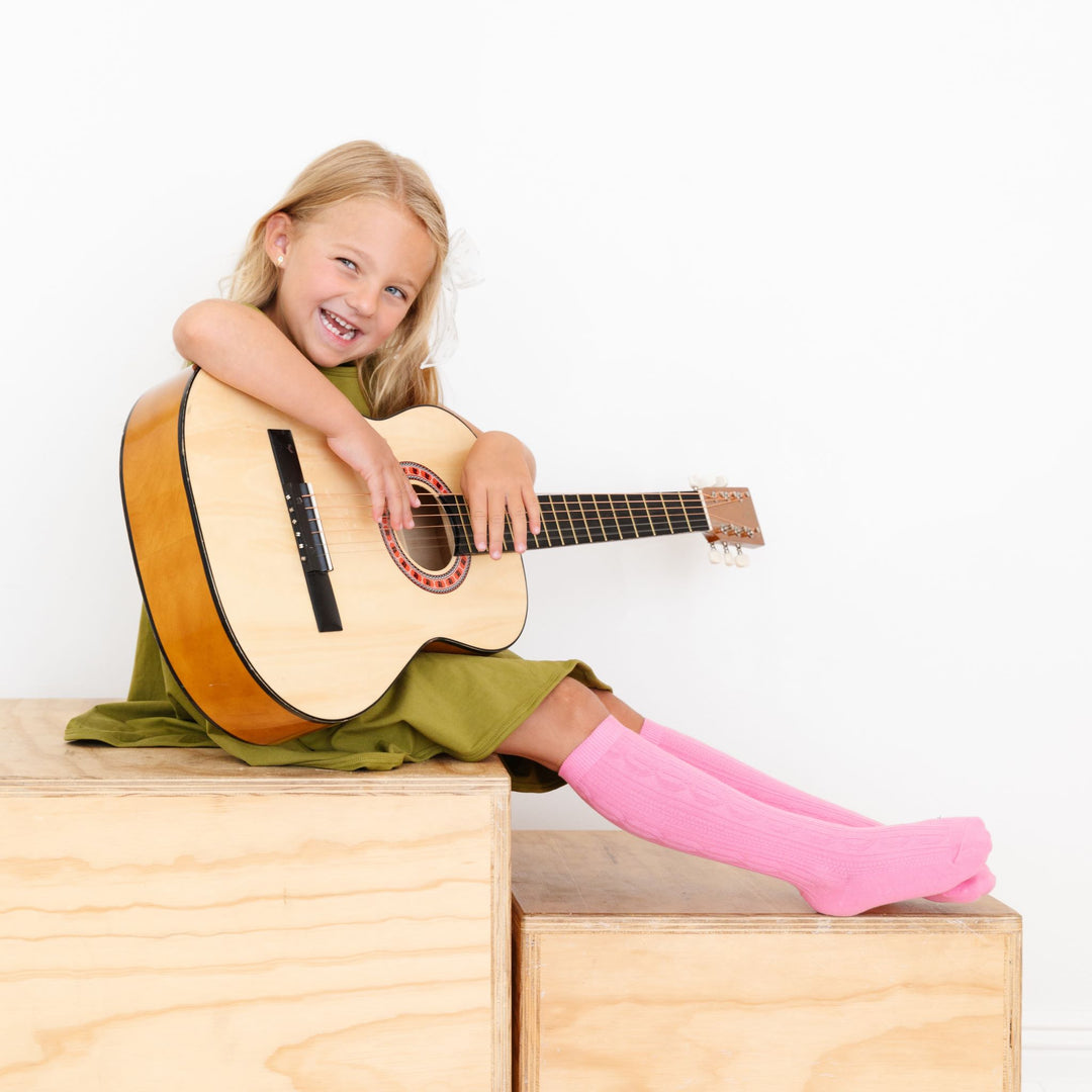 girl hoding guitar wearing taffy pink cable knit socks