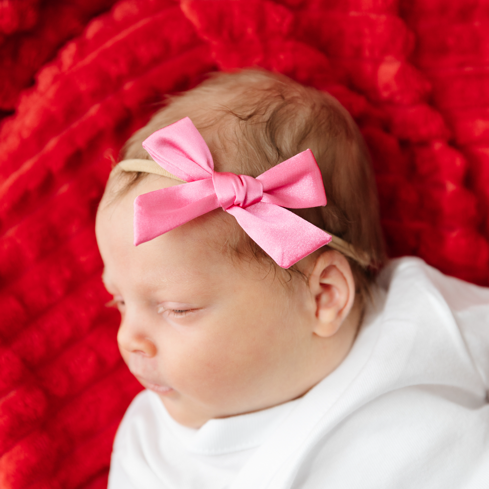 baby girl with pink satin hairbow on soft nylon headband