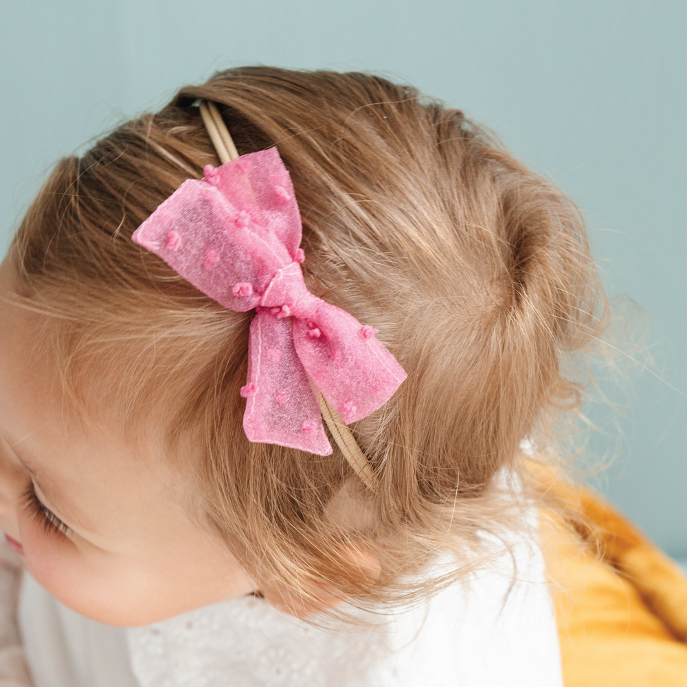 toddler girl wearing sheer pink swiss dot bow with nylon headband