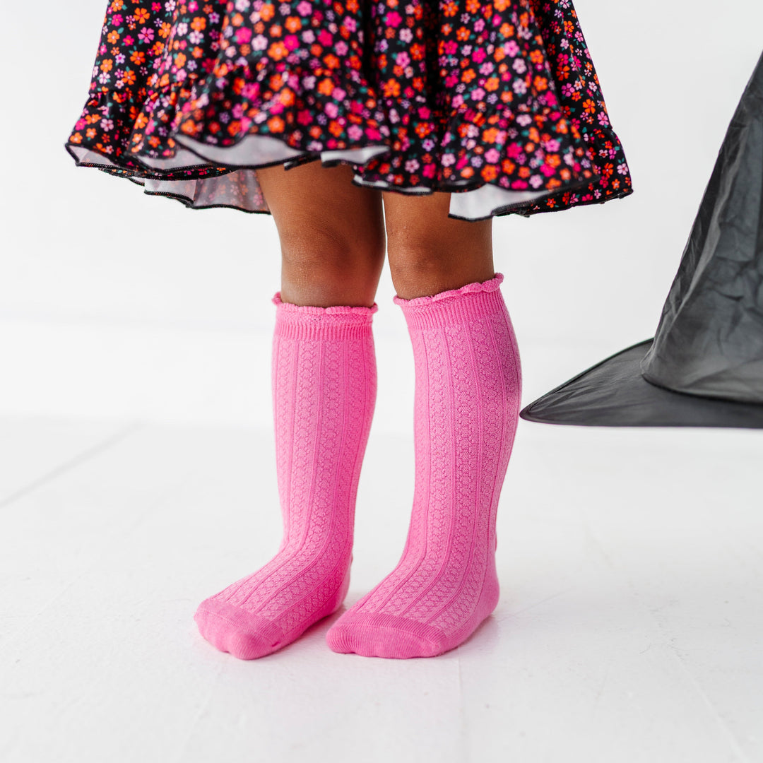little girl in black with orange and pink flower twirl dress paired pink knee socks with scalloped trim for Halloween