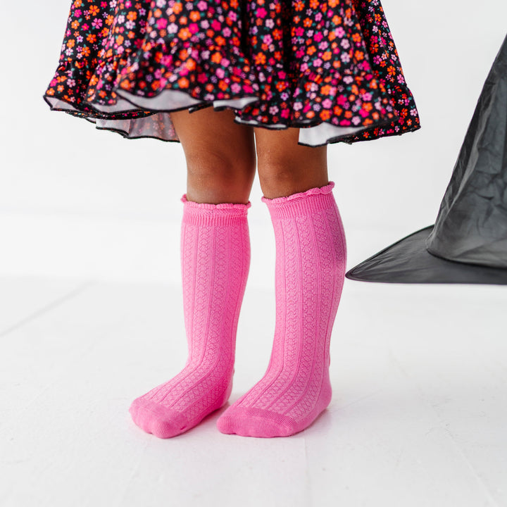 little girl in black with orange and pink flower twirl dress paired pink knee socks with scalloped trim for Halloween