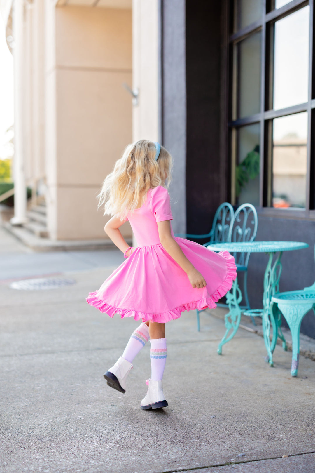 little girl twirling in pink dress with matching pastel striped knee highs