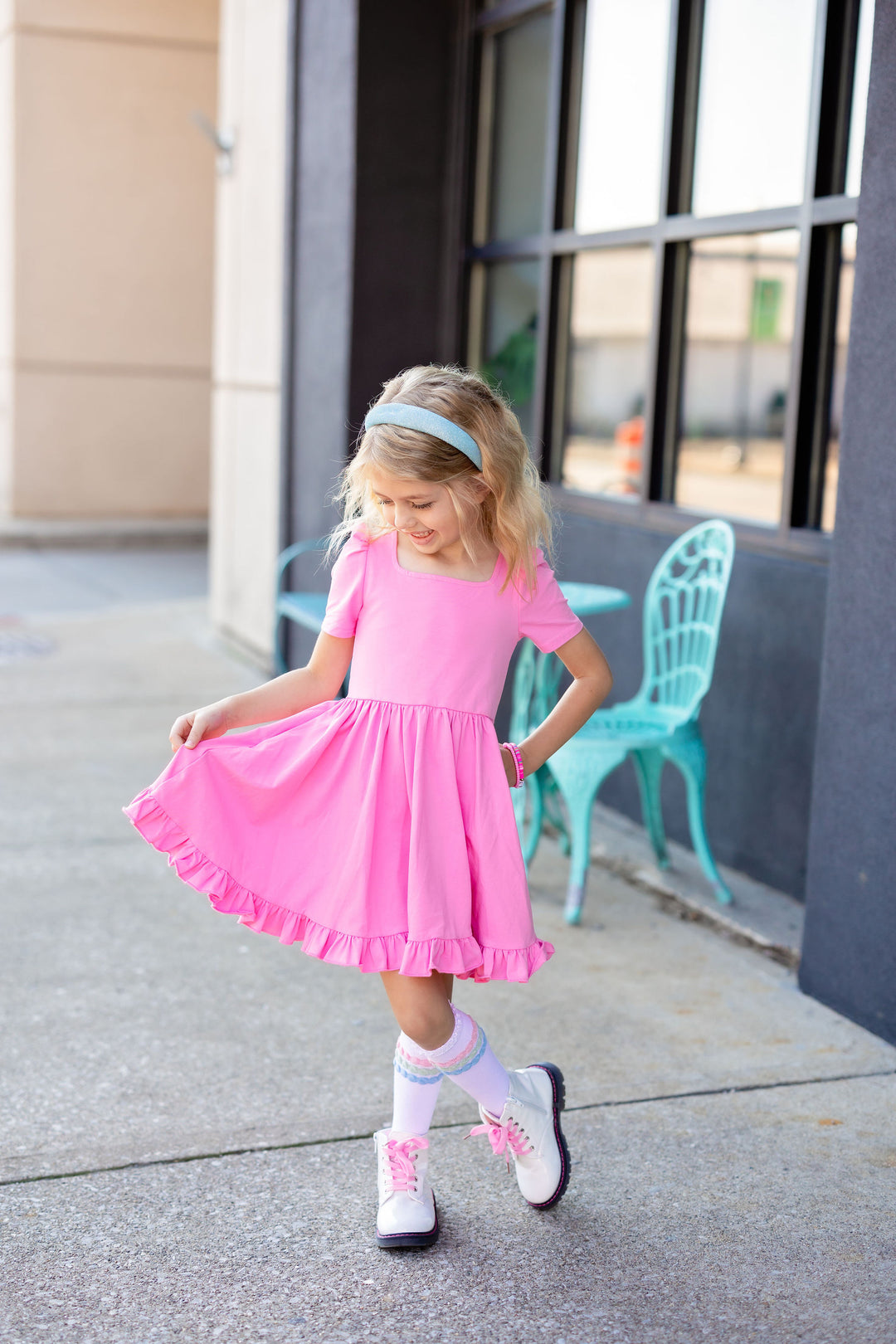 little girl in pink square neck twirl dress with matching pastel knee highs and light blue sparkly headband