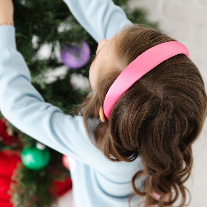 girl with pink satin headband by Christmas tree