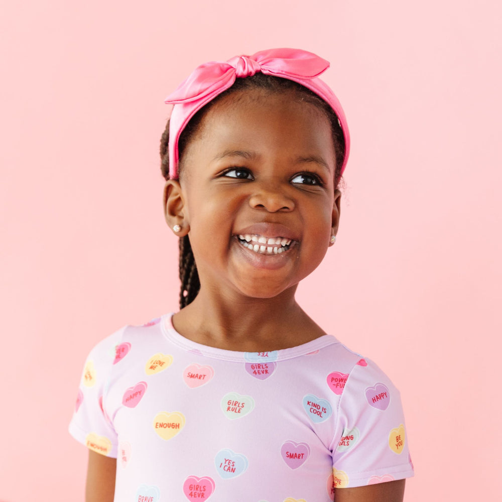 little girl in pink satin bow headband and matching lavender conversation heart inspired dress