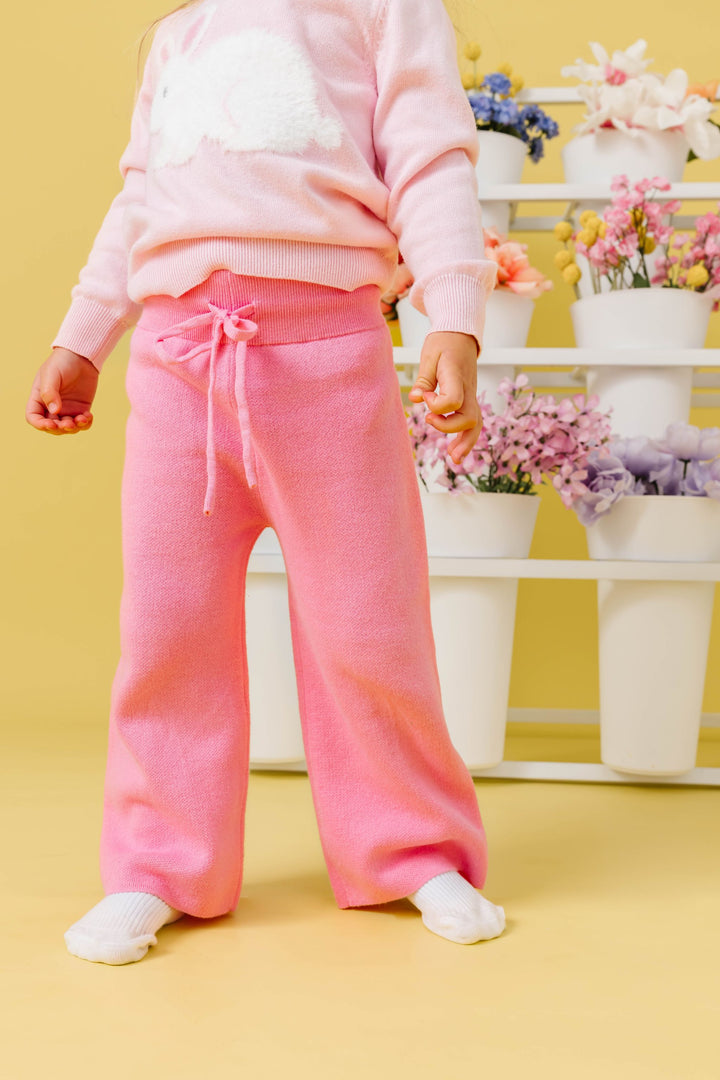 little girl in front of flower pots wearing pink cotton knit sweater pants paired with light pink fluffy bunny sweater for Easter