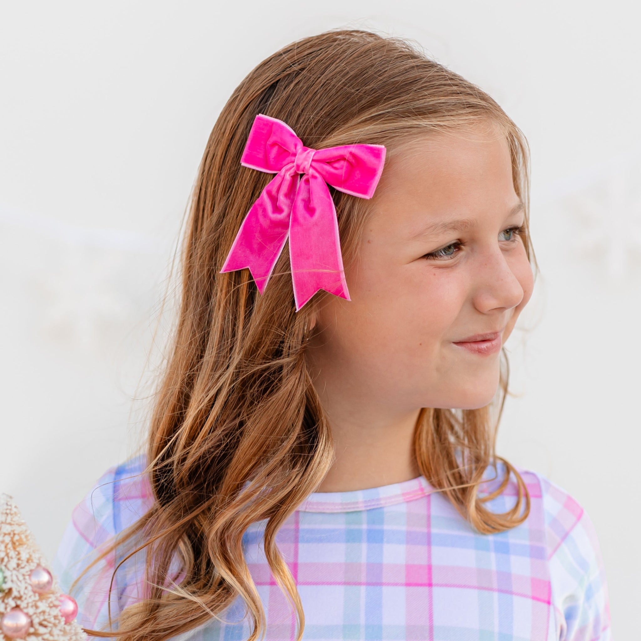 girl in bright pink velvet ribbon bow with dovetails on clip paired with winter plaid velvet outfit