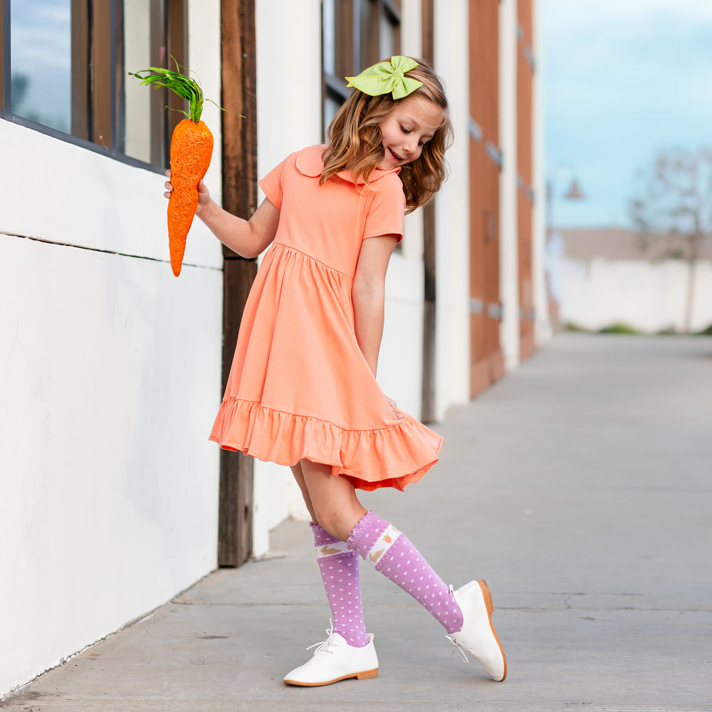 little girl in orange twirl dress and purple easter bunny socks