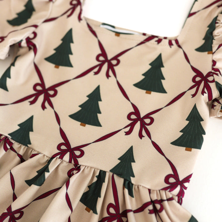 print closeup for cream Christmas dress with green tree and crimson ribbon print