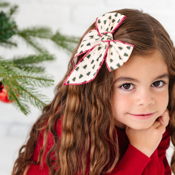 little girl with Christmas tree print hairbow with red trim and matching red holiday dress