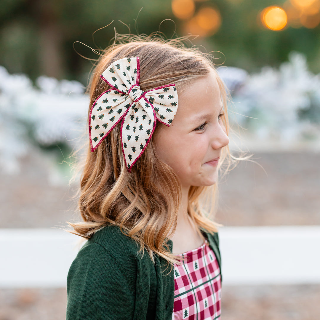 girl in christmas tree print bow with crimson trim and matching crimson gingham dress 