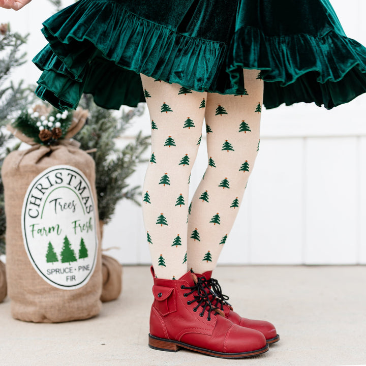 little girl in tree farm inspired outfit with green velvet dress and cream knit tights with tree design 