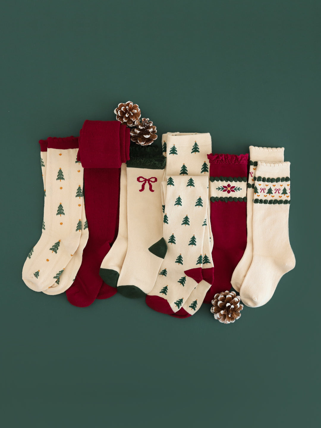flat lay photo of crimson, cream and forest green knee-high socks and tights with trees, bows and poinsettias to match vintage Christmas collection