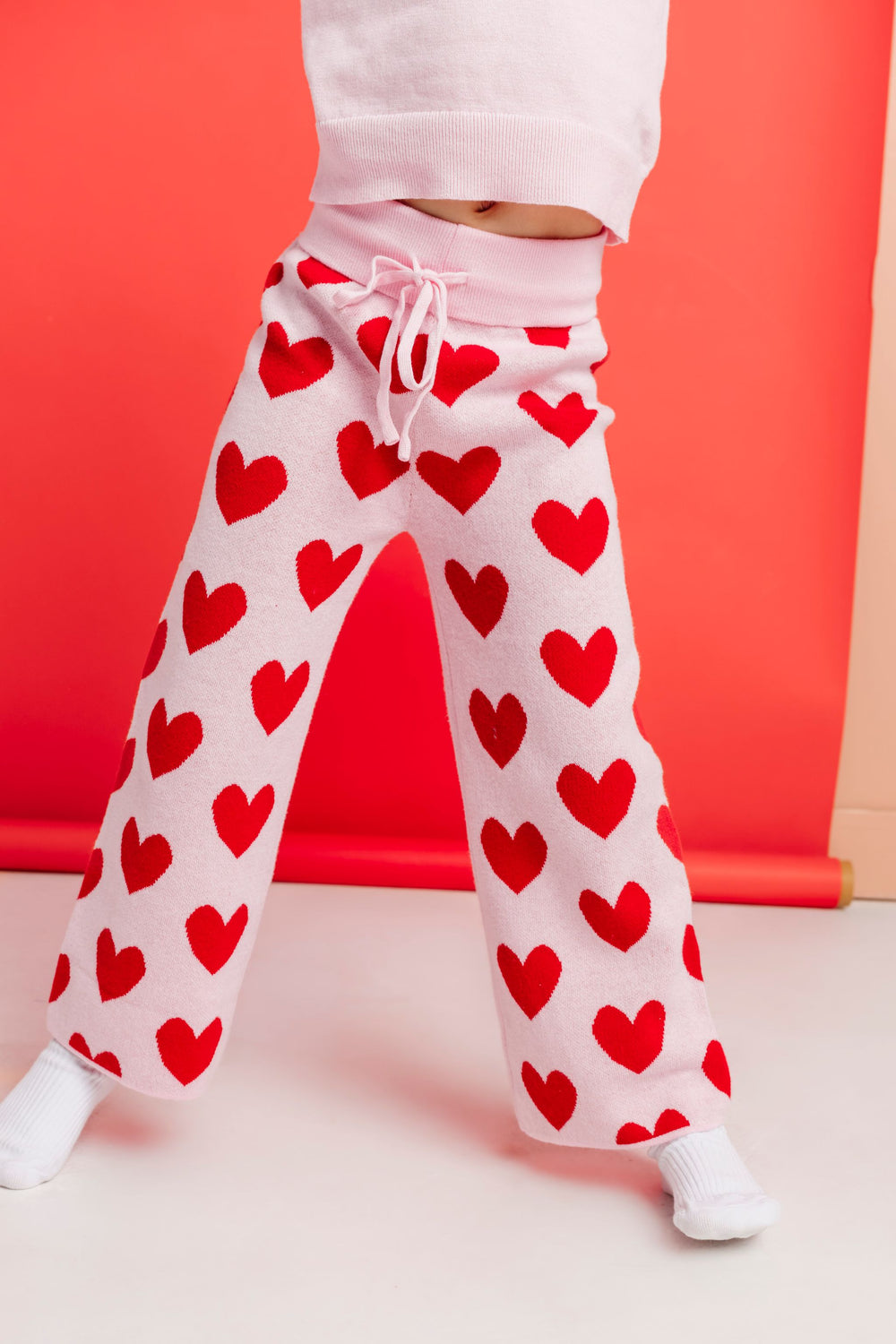 closeup of girl in light pink cotton knit sweater pants with red heart design for valentines day