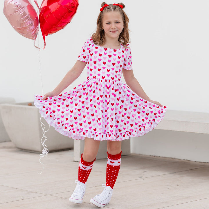 girl in valentines square neck twirl dress white with red and pink hearts and red dot heart socks