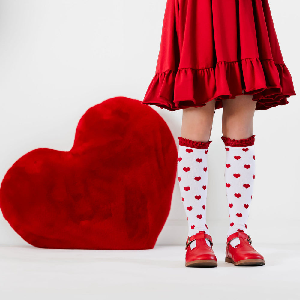 girl in red valentines dress wearing white and red heart knee high socks