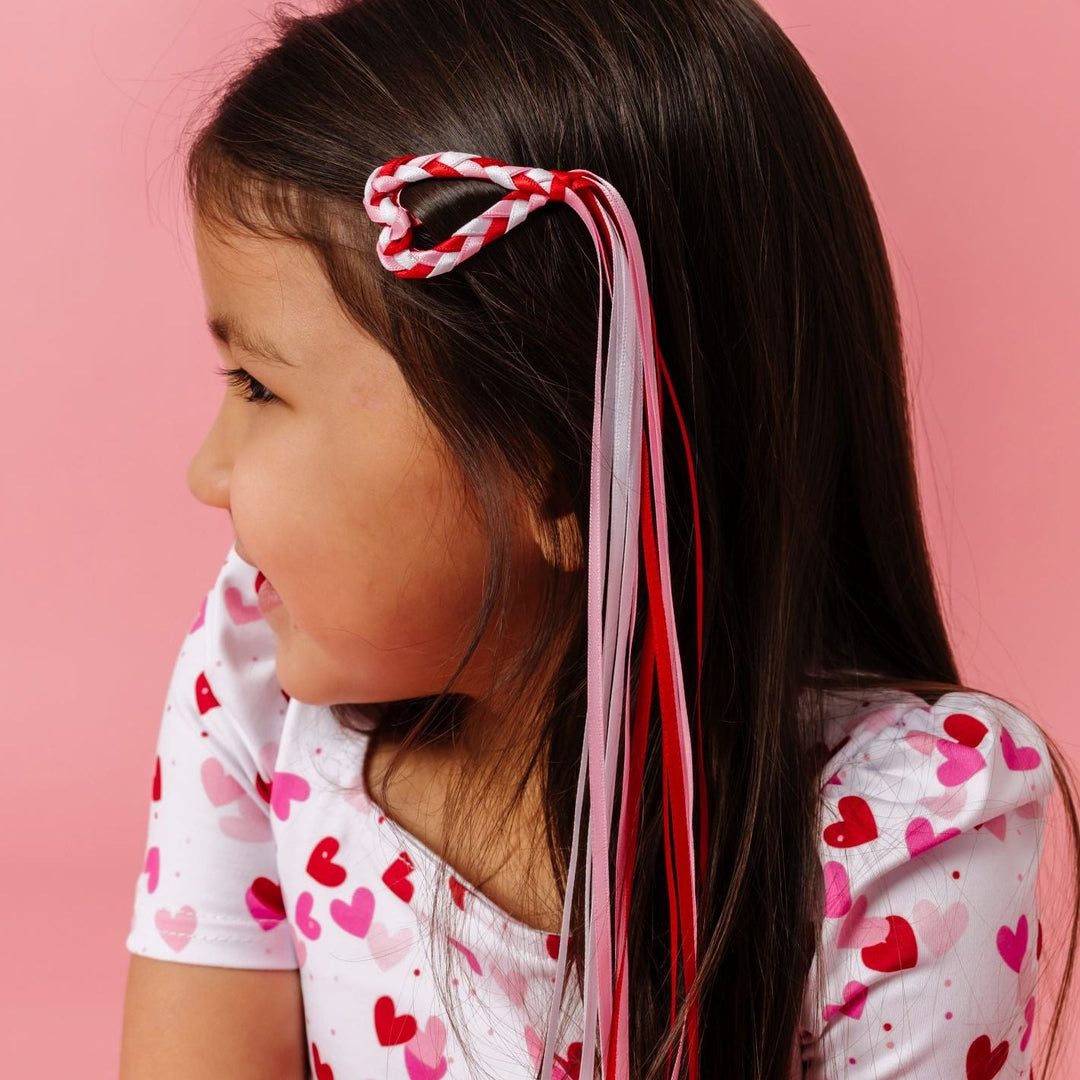 young girl in valentine's heart dress paired with heart shaped snap hair clip with braided ribbon streamers in red, white and pink