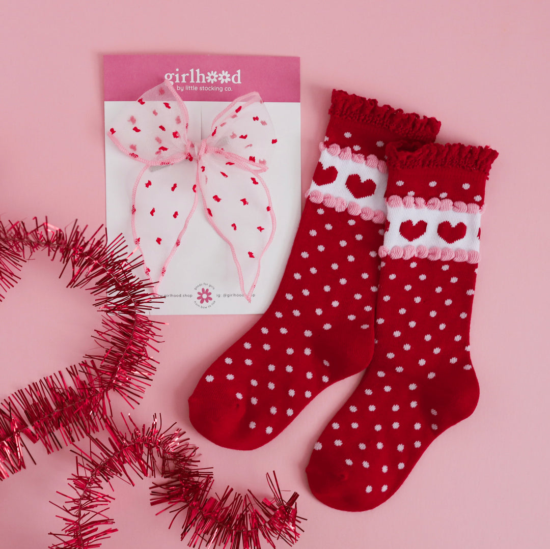 flat lay of sheer pink bow with red dots paired with red knee highs socks with white dots and hearts for Valentine's outfits