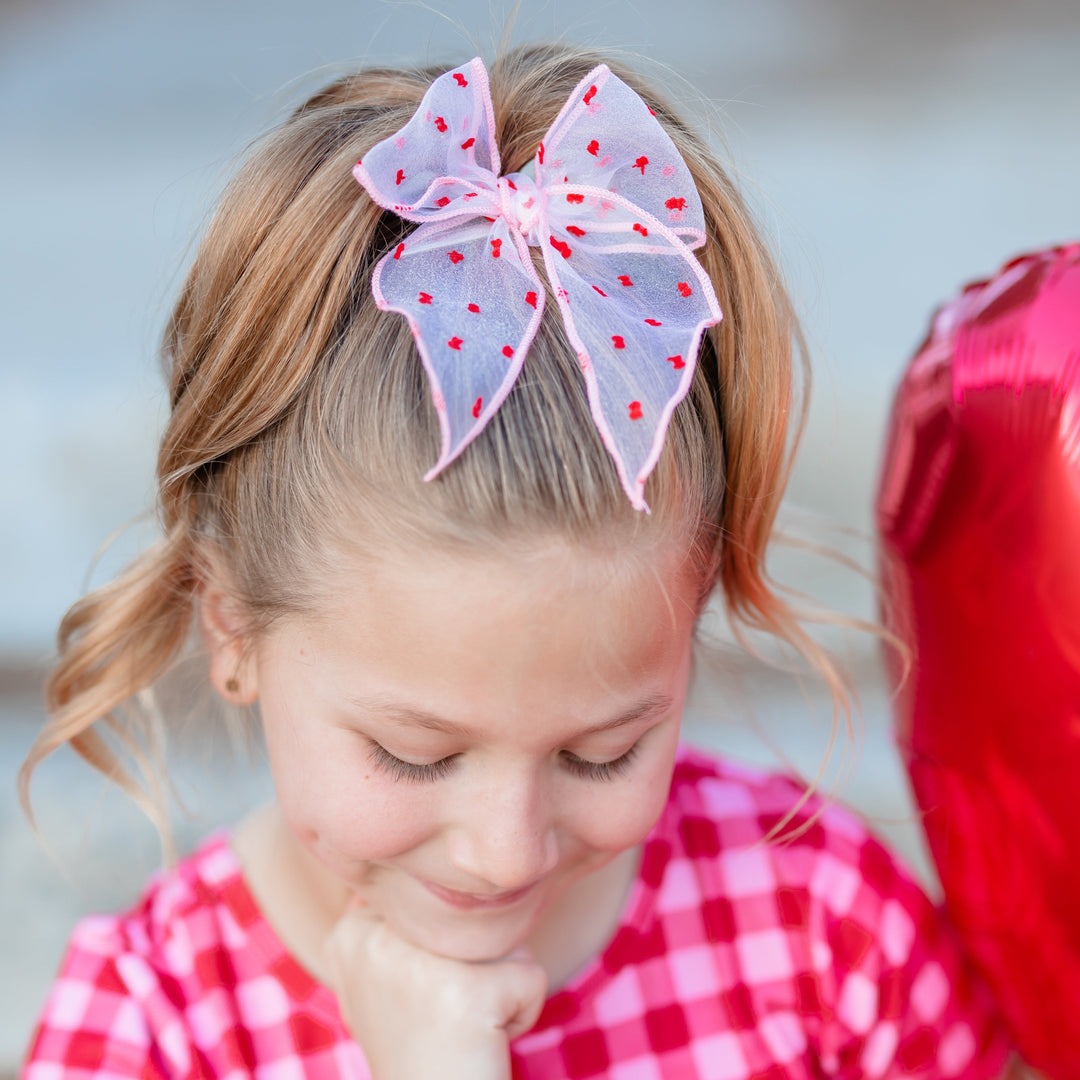 little girl in pink sheer bow with red dots and matching pink and red gingham valentine's dress