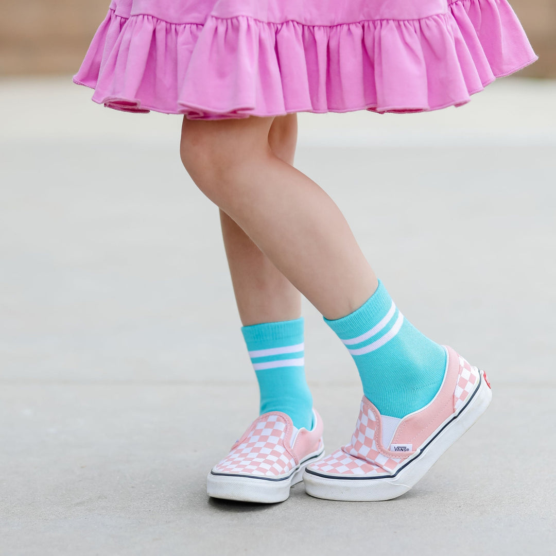 little girl in orchid twirl dress with turquoise and white striped midi socks and pink checkered vans