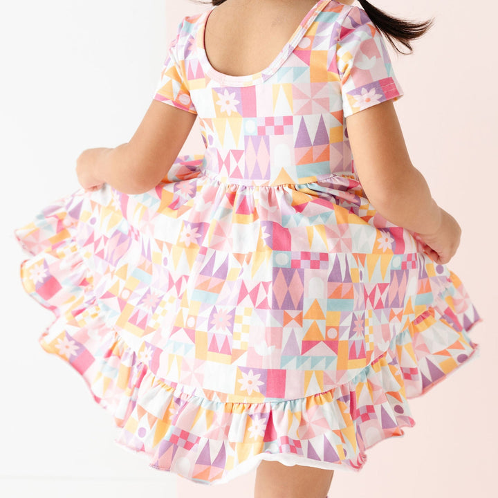 little girl twirling in geometric pattern dress inspired by Disneyland's Small World
