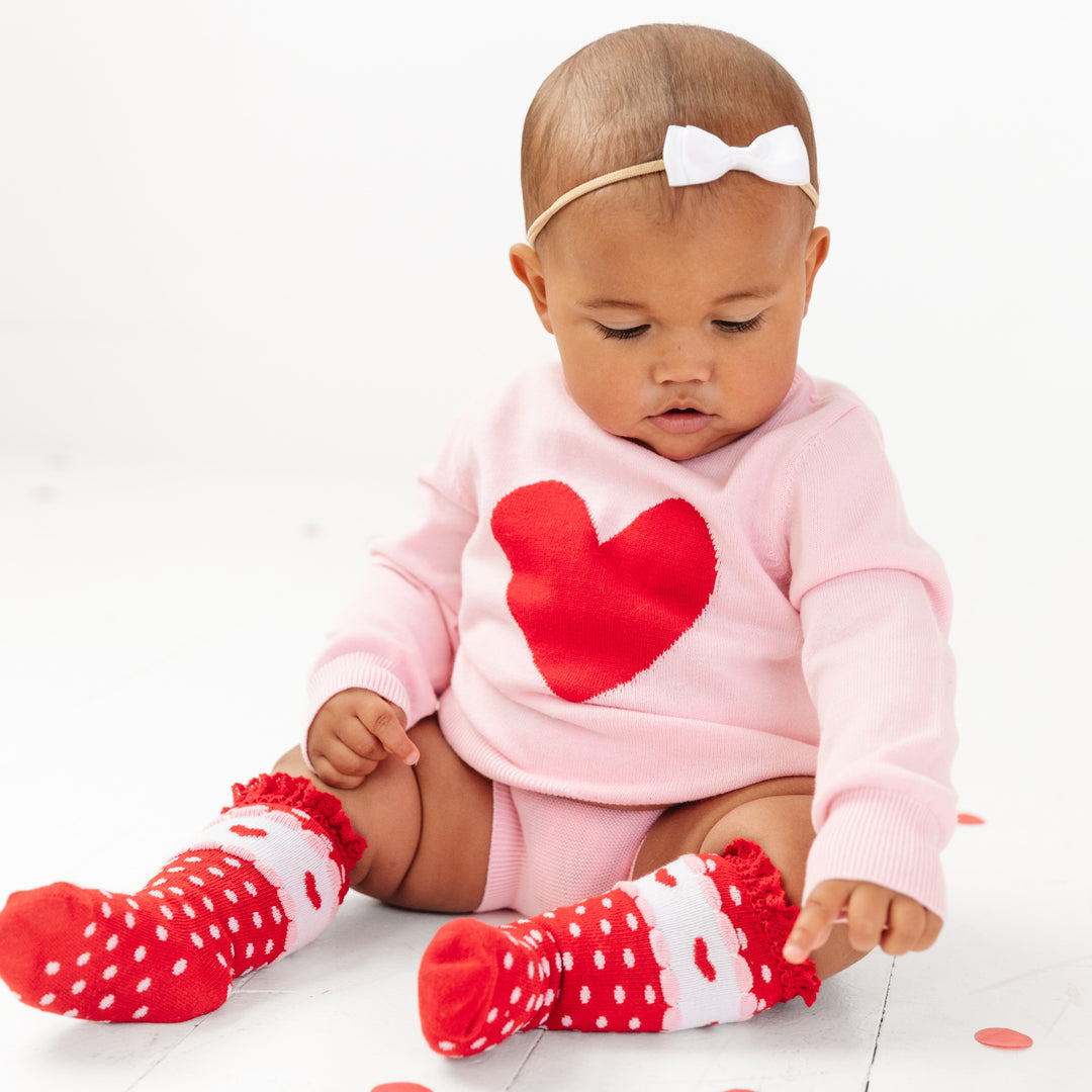 baby girl in pink heart sweater set and matching red knee highs with polka dot and heart details