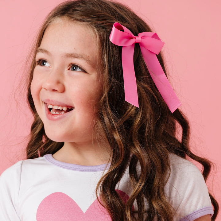 girl wearing girls taffy pink satin hair bow on alligator clip covered in matching satin with matching heart tee for valentine's day