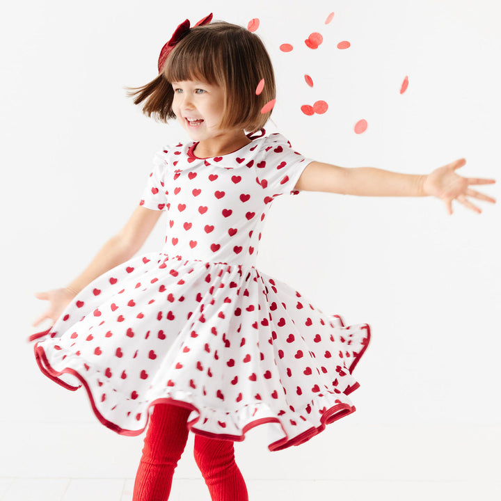 little girl twirling in white and red heart valentines day dress