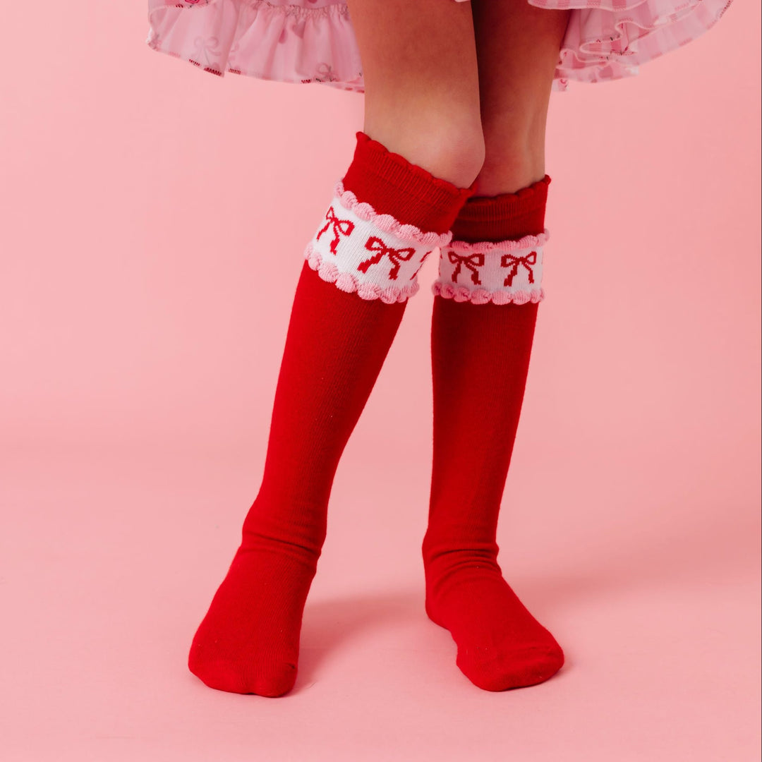 closeup of bright red scallop trimmed knee socks on little girl wearing cherry print twirl dress