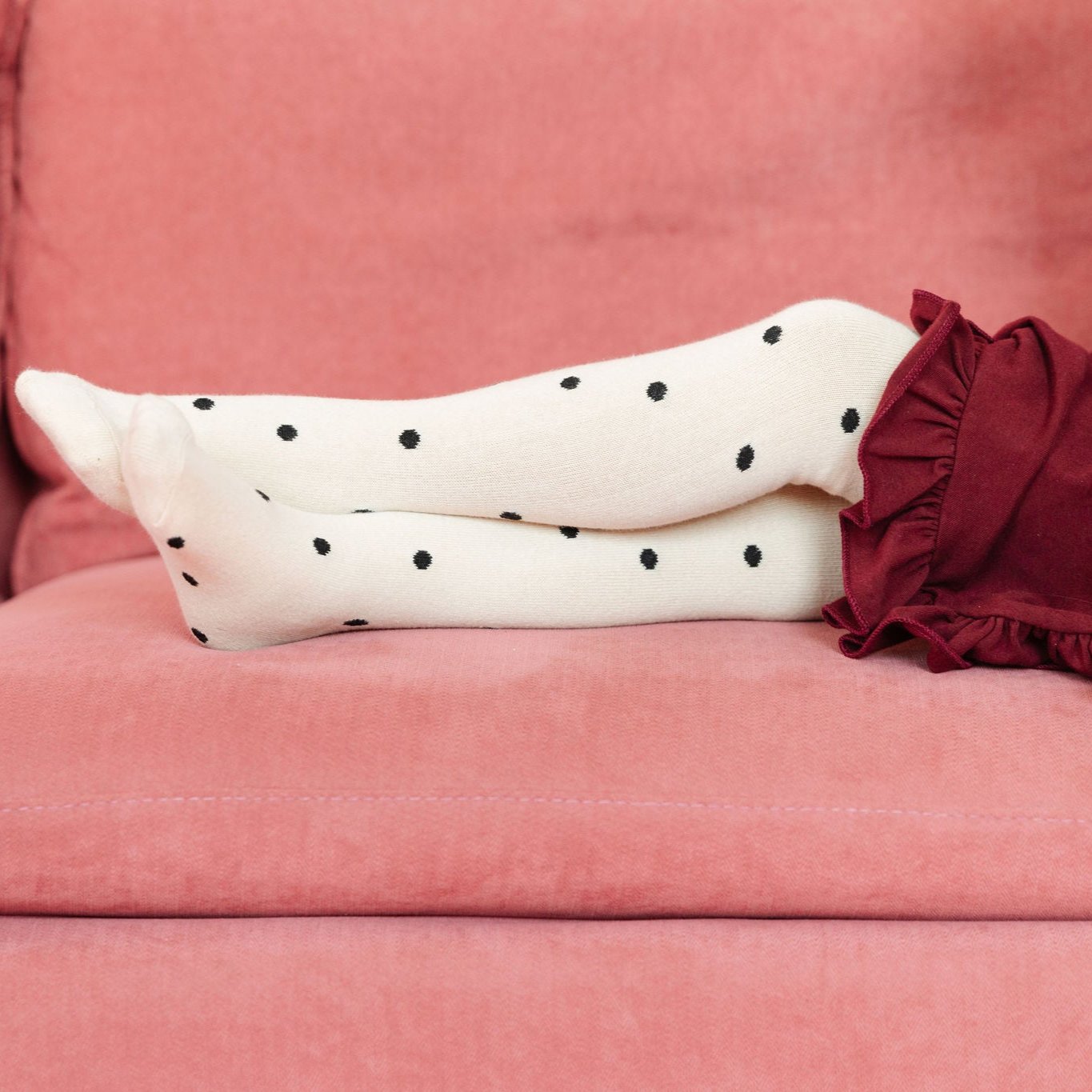 little girl on pink couch with neutral polka dot cotton tights