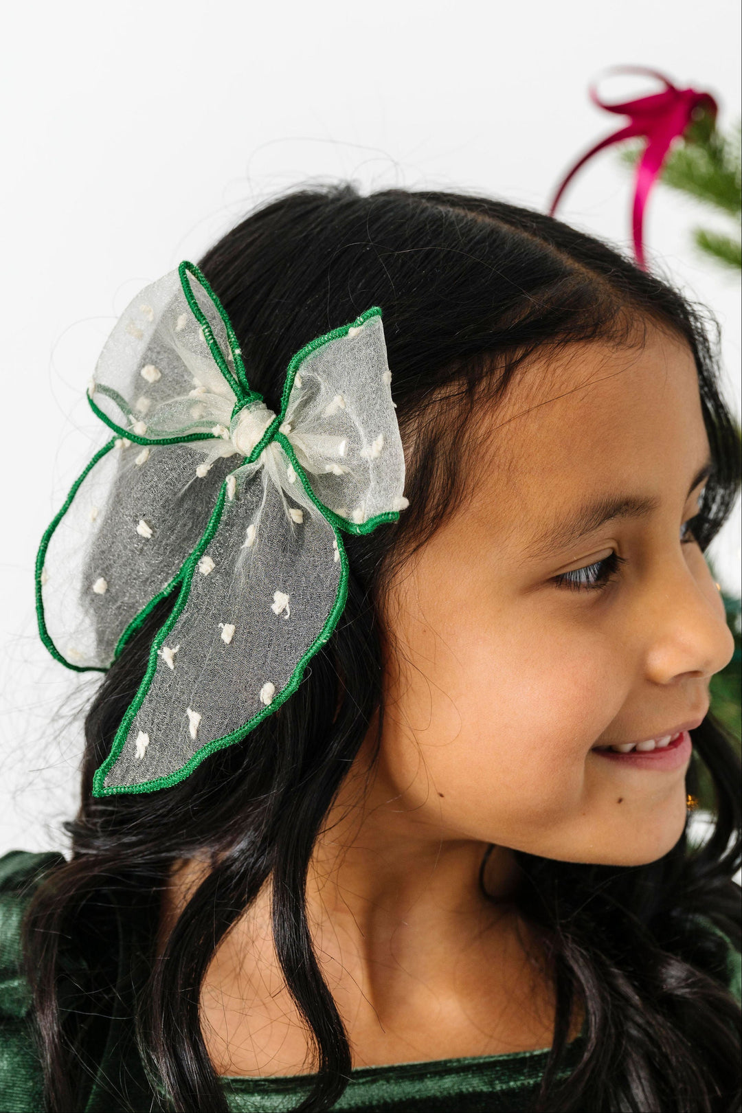 Young girl wearing a vanilla and green trim holiday hair bow .