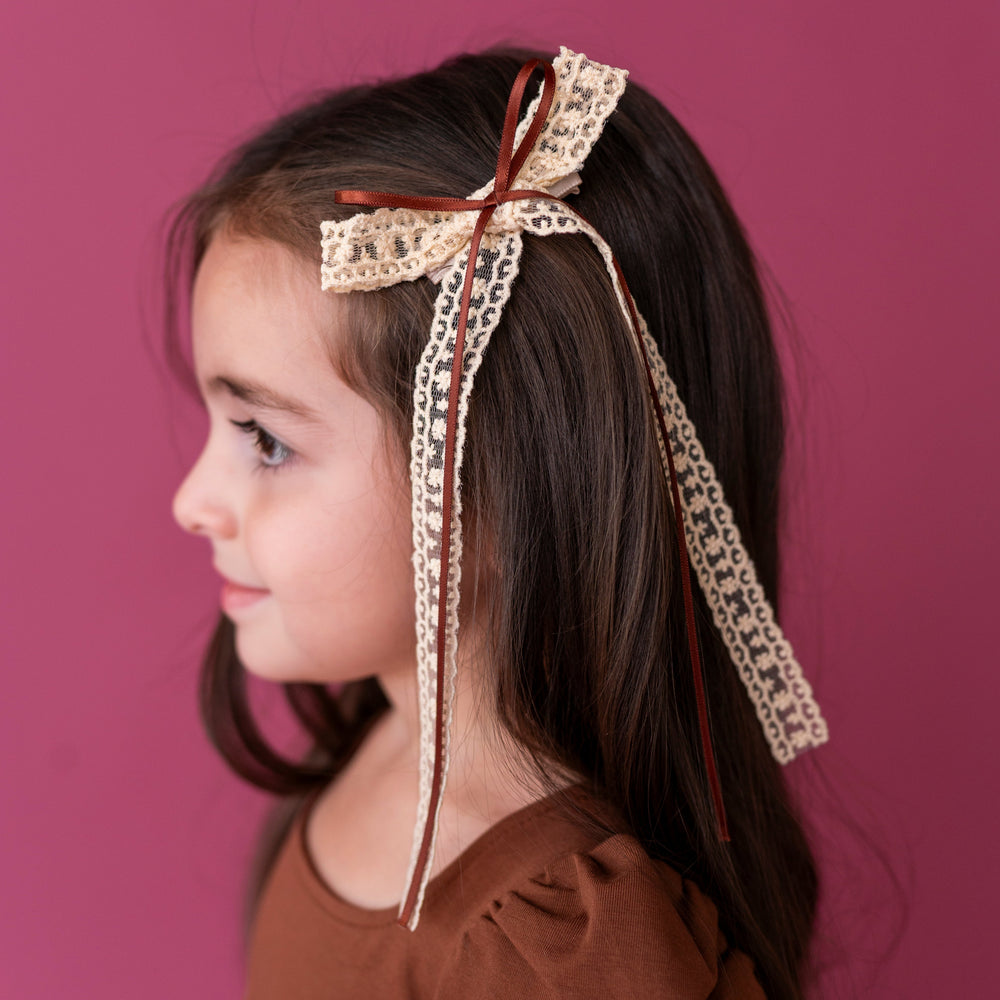 little girl in cream lace and brown ribbon long tail fall hair bow on clip paired with matching brown twirl dress