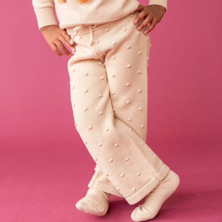 little girl in cream knit sweater pamnts with 3D bubble texture paired with matching sweater and socks