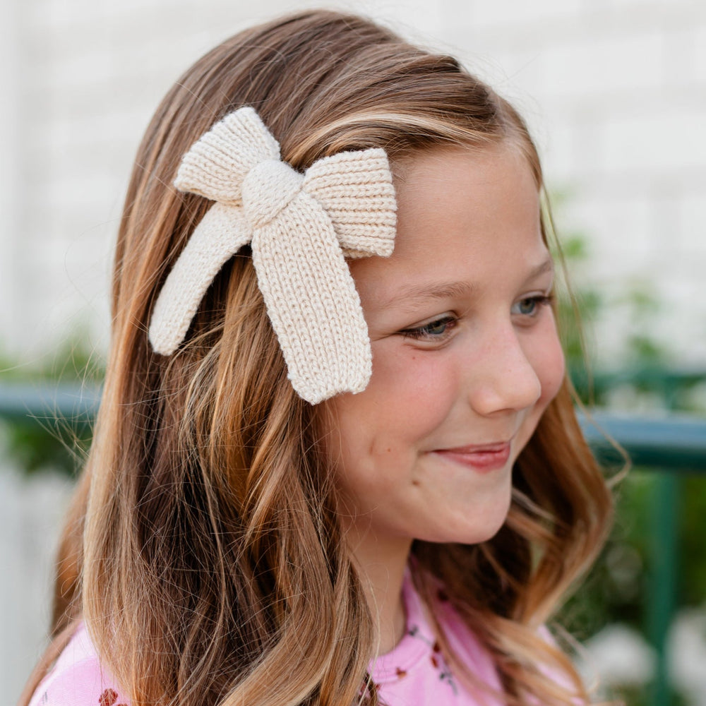 girl in cream knit bow on clip and pink velvet top with fall floral print