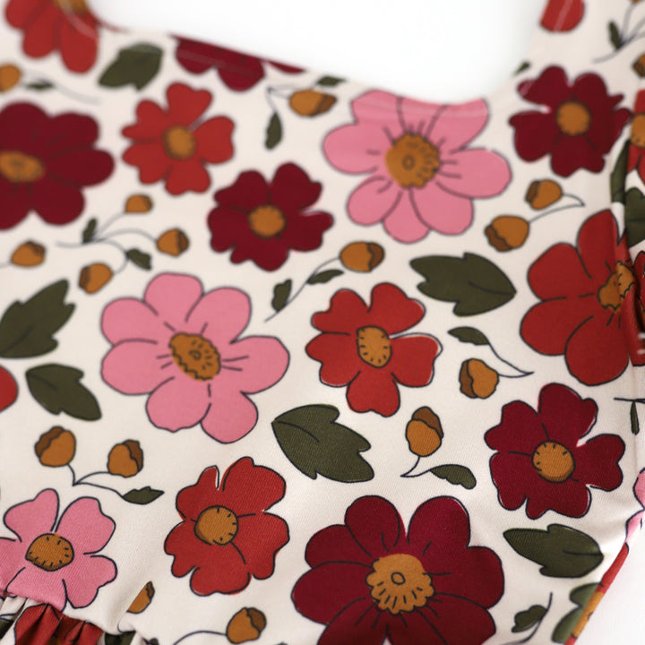 closeup of twirl dress floral print in shades of rust, burgundy and rose with olive and mustard accents on cream