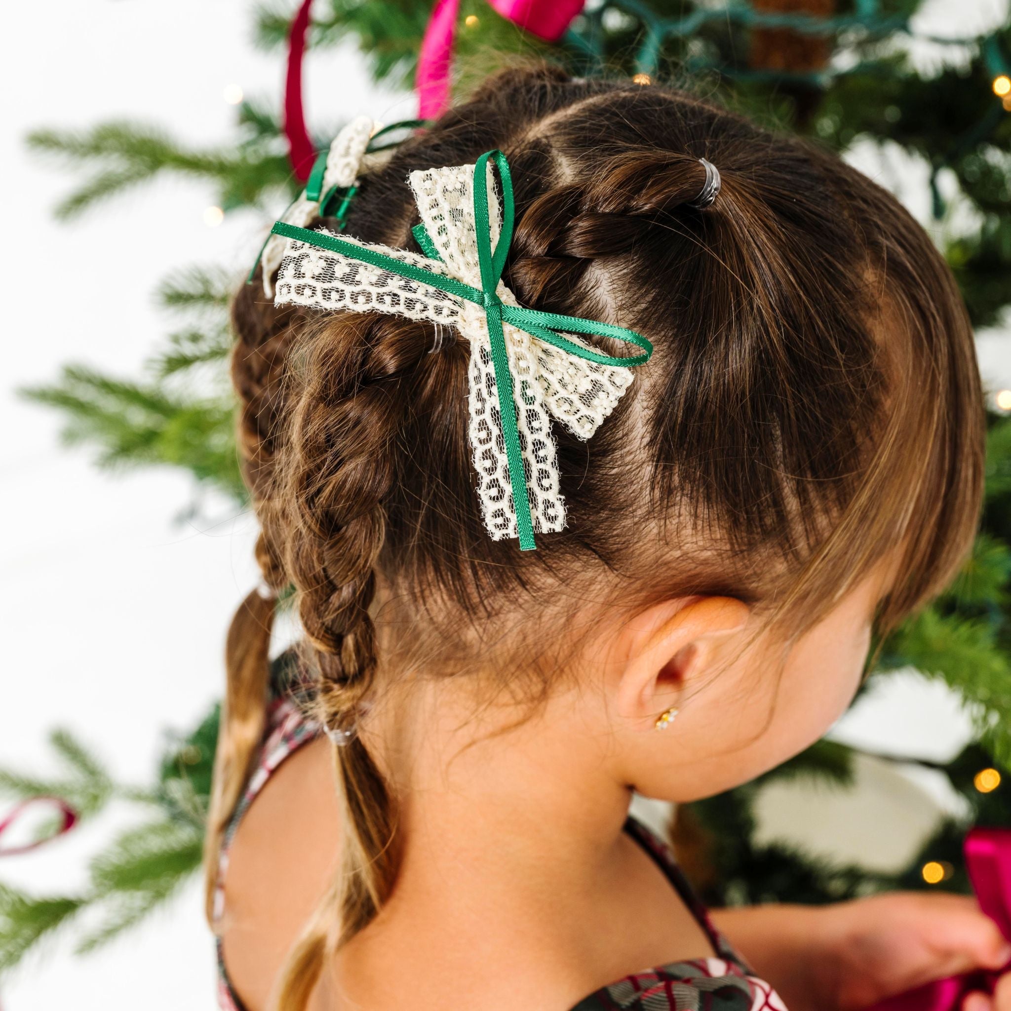 young girl decorating Christmas tree in forest plaid dress and matching cream lace bow with green satin ribbon accent