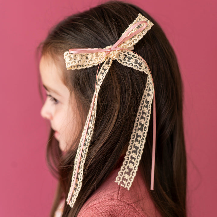 little girl in cream lace and rose pink ribbon hair bow paired with matching sweater